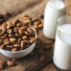 A white bowl of almonds and a glass of Almond milk