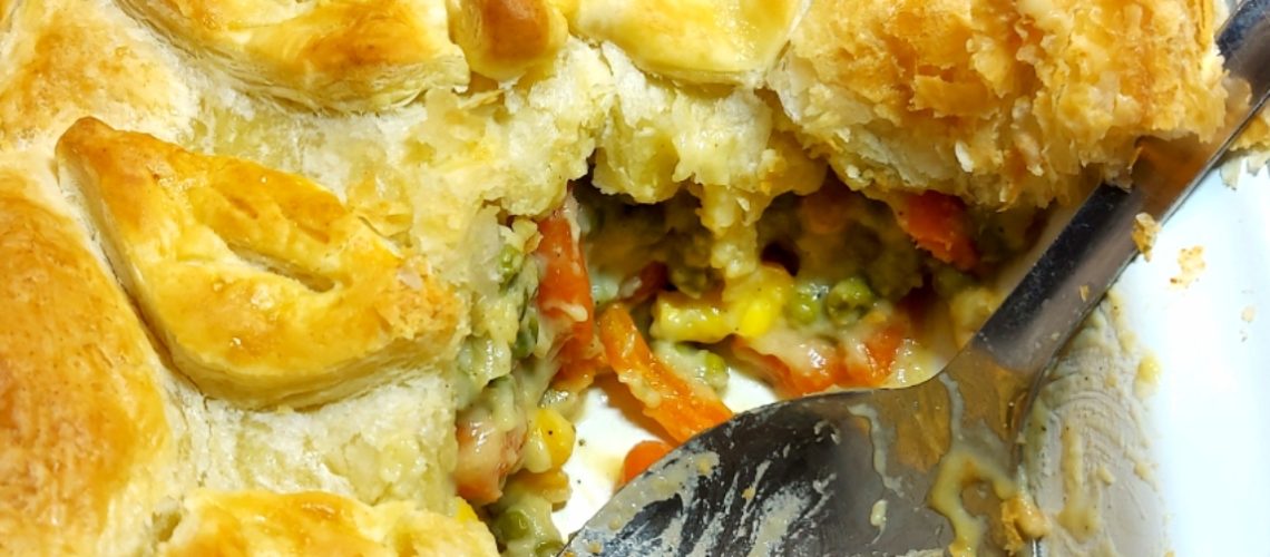 Vegan Vegetable Pie topped with puff pastry with a portion removed