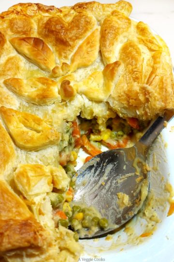 Vegan Vegetable Pie topped with puff pastry with a portion removed