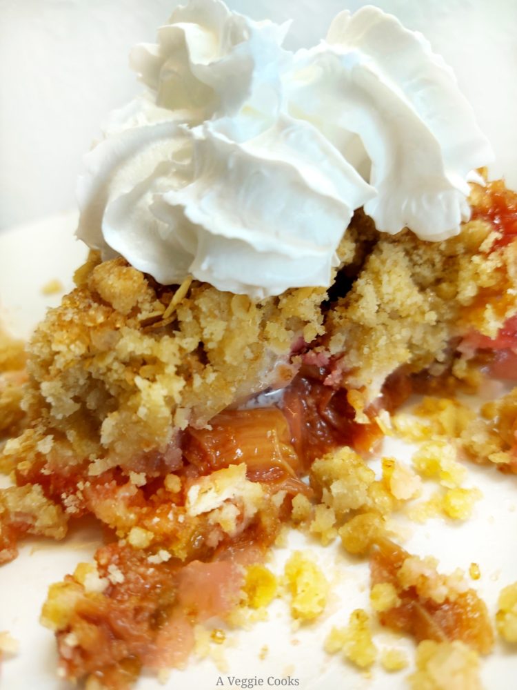 Rhubarb crumble on a plate with vegan cream