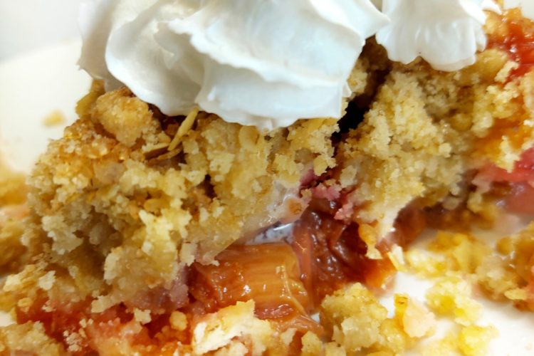 Rhubarb crumble on a plate with vegan cream