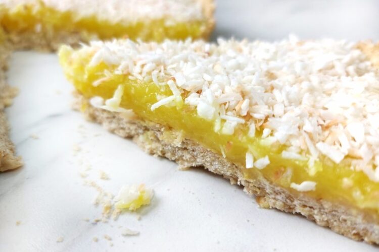 Vegan lemon slice topped with coconut on a white surface