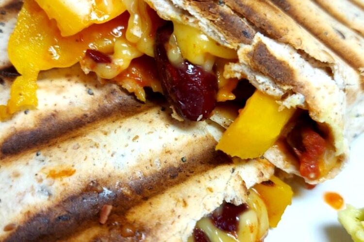 Cooked tortilla wrap with salsa, yellow pepper, kidney beans and vegan cheese