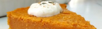 Slice of Vegan pumpkin pie with rest of pie in dish behind
