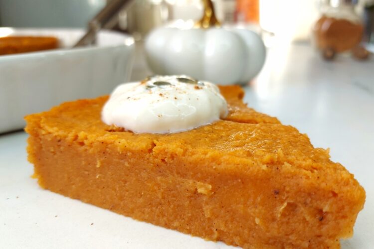 Slice of Vegan pumpkin pie with rest of pie in dish behind