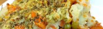 Portion of vegan shepherd’s pie on a white plate with rest of pie in the background
