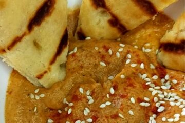Baba Ganoush in a bowl with sesame seeds and grilled bread wedges
