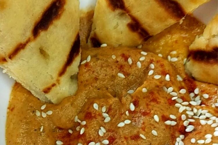 Baba Ganoush in a bowl with sesame seeds and grilled bread wedges